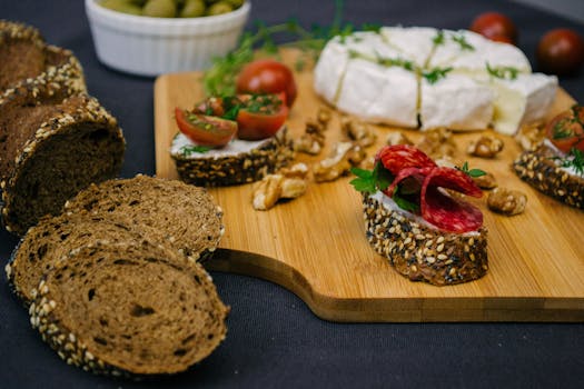 Plateau apéritif avec pains sans pétrissage, tapenade, fromage, tomates cerises et noix sur une planche en bois.